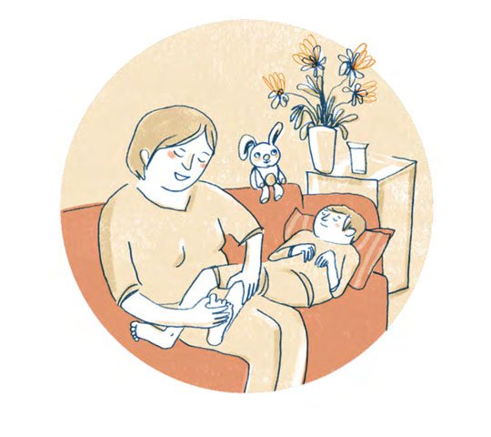 Eine Mutter sitzt auf dem Sofa. Ihr Sohn liegt neben ihr. Seine Beine liegen auf den Oberschenkeln der Mutter. Sie streichelt mit einer Hand die Wade ihres Sohnes. Mit der anderen Hand streichelt sie seine Zehen.